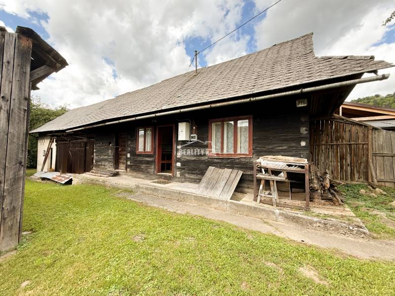 Eine Holzhütte in Papradno mit grasbewachsener Umgebung und einem Holzzaun.