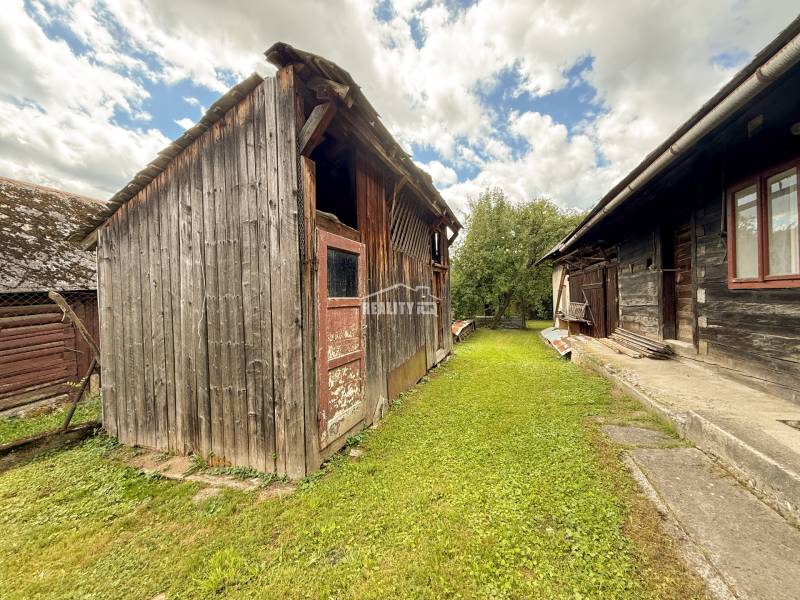 Holzgebäude bei der Hütte in Papradno, umgeben von Grün und blauem Himmel.