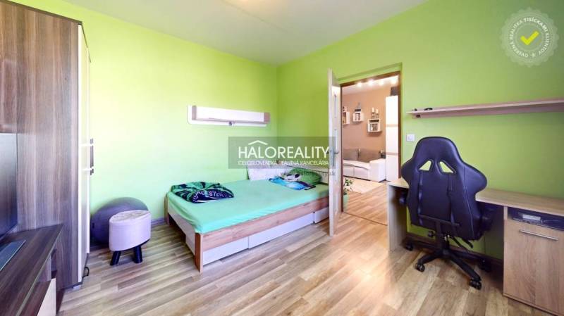 Ein Zimmer in einer 2-Zimmer-Wohnung mit Holzboden, grünen Wänden und einer Arbeitsecke.