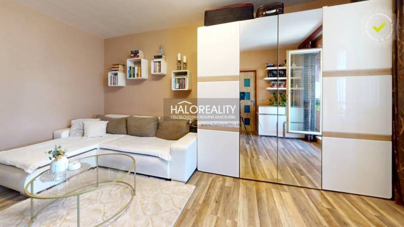 Wohnzimmer in einer 2-Zimmer-Wohnung mit einem weißen Sofa und einem Spiegelschrank.