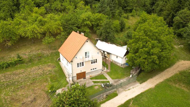 Ein Einfamilienhaus in Papradno, umgeben von einem grasbewachsenen Grundstück und Bäumen, mit einer Zufahrtsstraße.