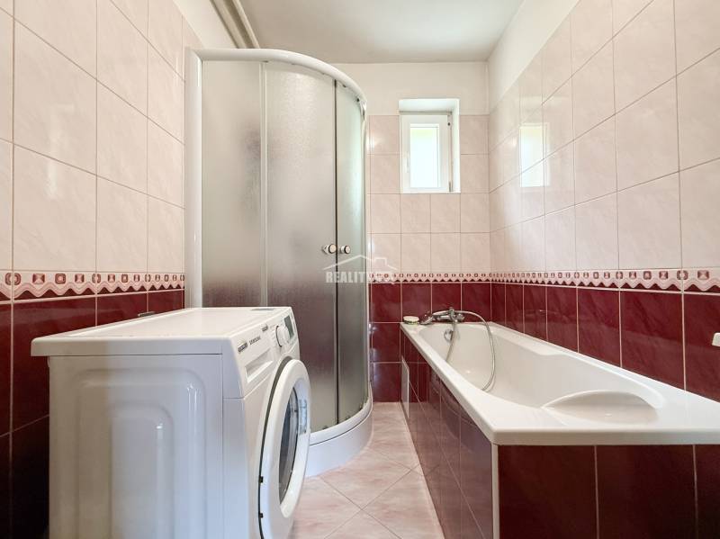 Badezimmer mit Badewanne, Dusche und Waschmaschine in einem Einfamilienhaus.
