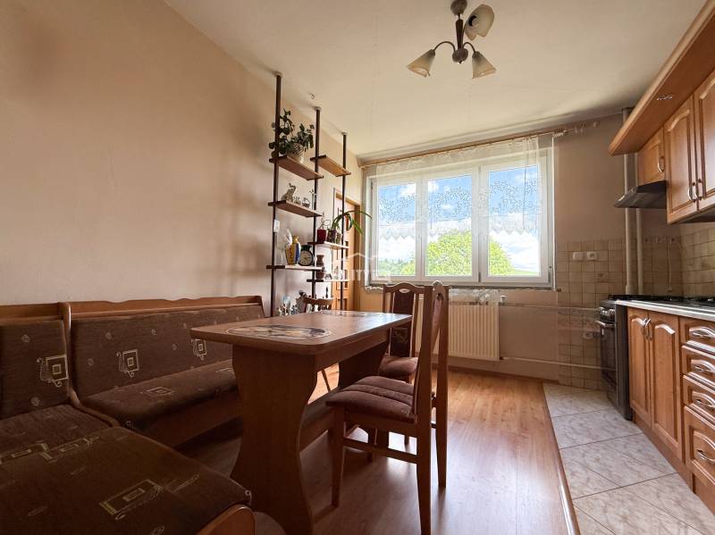 Ein Einfamilienhaus mit einer Küche, die Holzmöbel, einen Esstisch und ein Regal mit Dekorationen enthält.