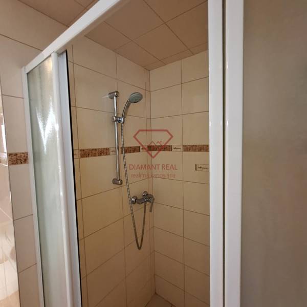 Duschkabine in einem Einfamilienhaus mit Keramikfliesen und verstellbarem Duschkopf.