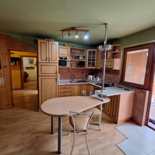 Die Küche eines Einfamilienhauses mit Holzmöbeln, einem Tisch und bordeauxroten Wänden.
