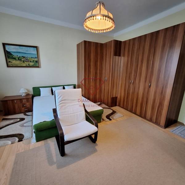 Schlafzimmer in einem Einfamilienhaus mit Bett, Sessel, großem Schrank und Bild an der Wand.