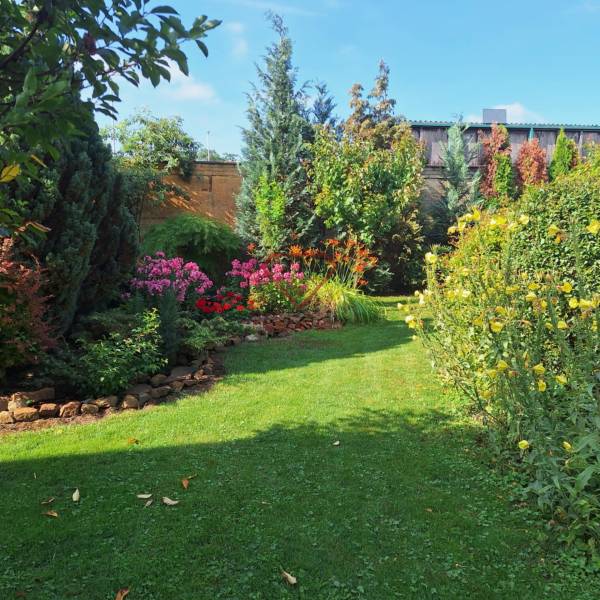 Ein Garten mit Blumenbeeten und Bäumen hinter einem Einfamilienhaus in der Šalská-Straße in Šaľa.