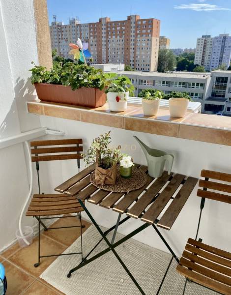 Balkon einer 3-Zimmer-Wohnung mit Holzmöbeln und Blick auf Petržalka.