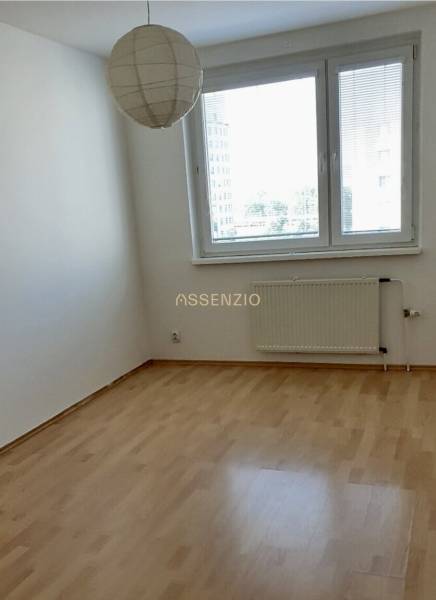 Ein leerer Raum mit Holzboden, Heizkörper und Fenster in einer 3-Zimmer-Wohnung.