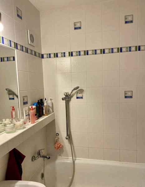 Badezimmer mit Badewanne und Regal für Kosmetik in einer 3-Zimmer-Wohnung.