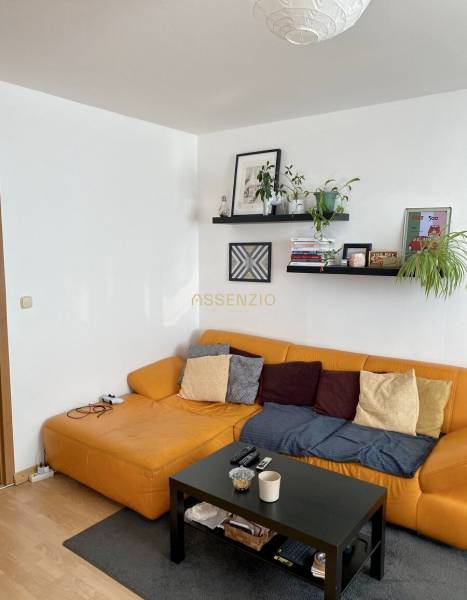 Wohnzimmer mit gelbem Sofa und schwarzem Tisch in einer 3-Zimmer-Wohnung.