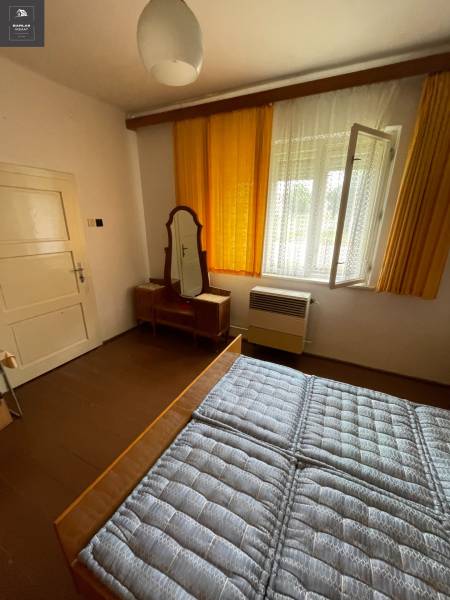 Schlafzimmer im Einfamilienhaus mit Fenster, Spiegel und Bett mit gestepptem Matratze.
