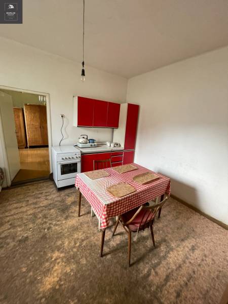 Eine Küche in einem Einfamilienhaus mit einem Esstisch und einer roten Küchenzeile.