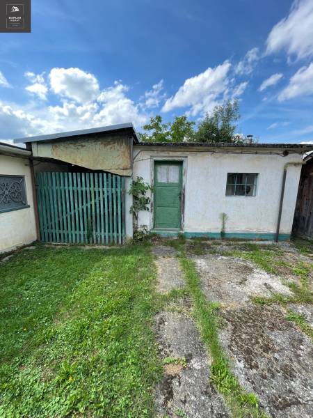 Ein Einfamilienhaus in Trenčianske Stankovce mit grüner Tür, kleinem Fenster und Rasen.