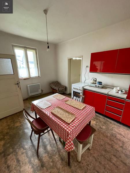 Eine Küche in einem Einfamilienhaus mit einer roten Küchenzeile und einem Esstisch.