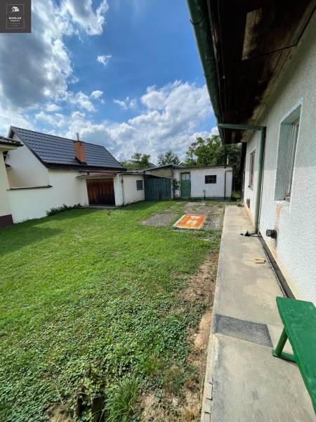 Der Garten des Einfamilienhauses in Trenčianske Stankovce mit grünem Rasen und Anbau.