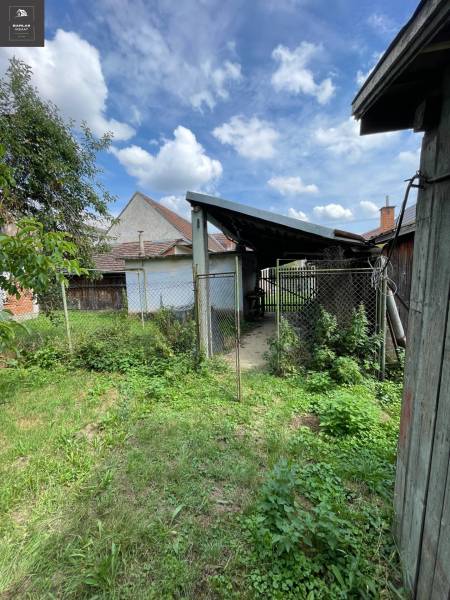 Der Garten eines Einfamilienhauses in Trenčianske Stankovce mit Rasen und einem Unterstand unter blauem Himmel.