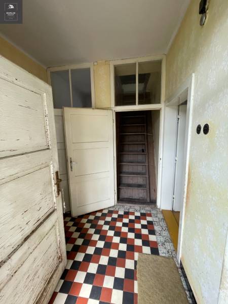 Eingangsflur in einem Einfamilienhaus mit kariertem Boden und Holztreppe.