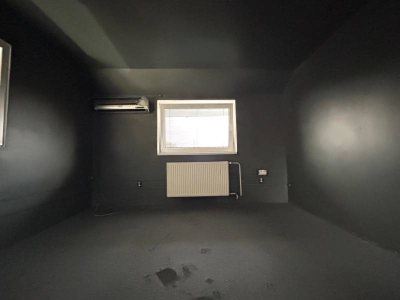Ein dunkles Zimmer in einer 4-Zimmer-Wohnung mit Klimaanlage und Heizkörper unter dem Fenster.