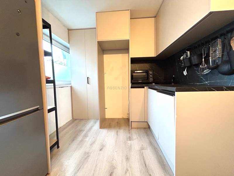 Küche in einer 4-Zimmer-Wohnung mit Holzboden, eingebauten Geräten und Stauraum.