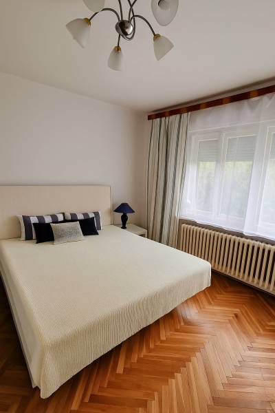 Helles Schlafzimmer im Einfamilienhaus mit Bett, Lampe und Holzboden.