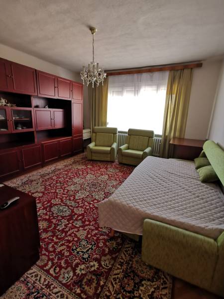 Ein Zimmer in einem Einfamilienhaus, enthält ein Bett, Sofas, einen Teppich und einen Wandschrank.