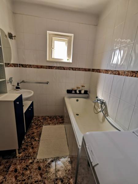 Ein Badezimmer in einem Einfamilienhaus mit eingebauter Badewanne und Waschbecken, gefliest mit hellen Fliesen.