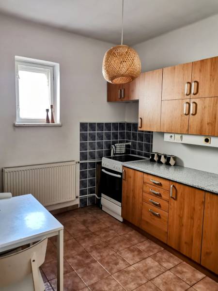 Eine Küche in einem Einfamilienhaus mit Holzschränken, einem Herd und einem weißen Tisch.