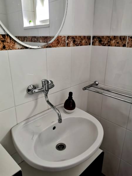 Waschbecken in einem Einfamilienhaus mit rundem Spiegel und Fliesen mit braunem Muster.
