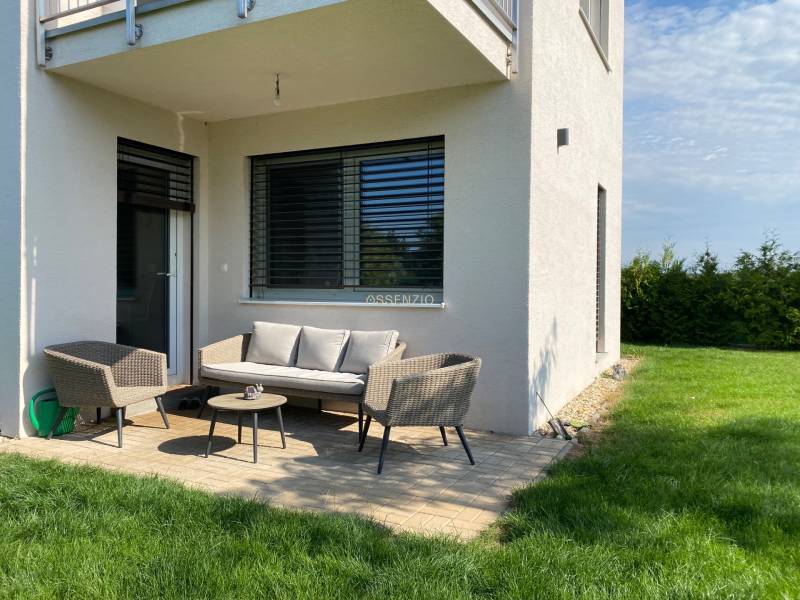 Ein Einfamilienhaus in Vojka nad Dunajom mit Terrasse, Gartenmöbeln und Rasen.