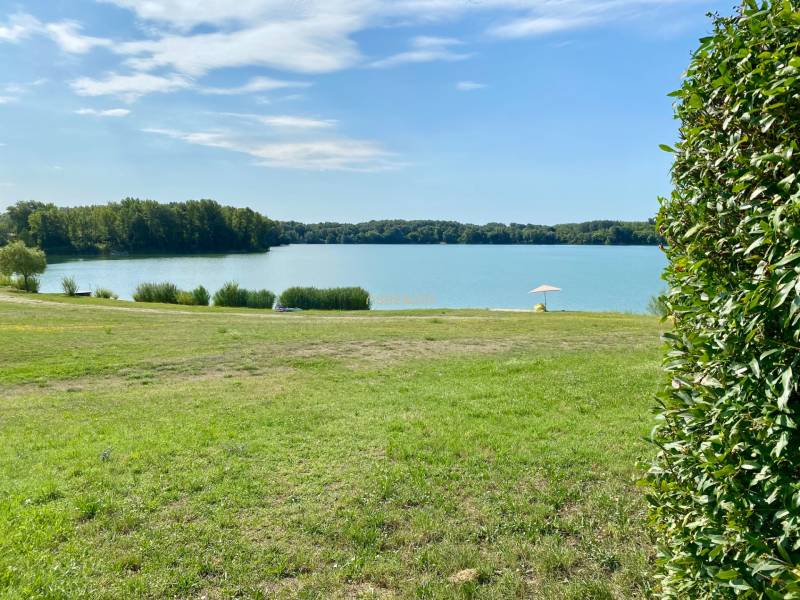 Ein ruhiger Wasserbereich bei einem Einfamilienhaus in Vojka nad Dunajom mit Grünflächen und einem Sonnenschirm.