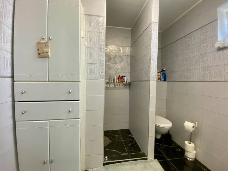 Badezimmer im Einfamilienhaus mit Keramikfliesen und Stauraum.