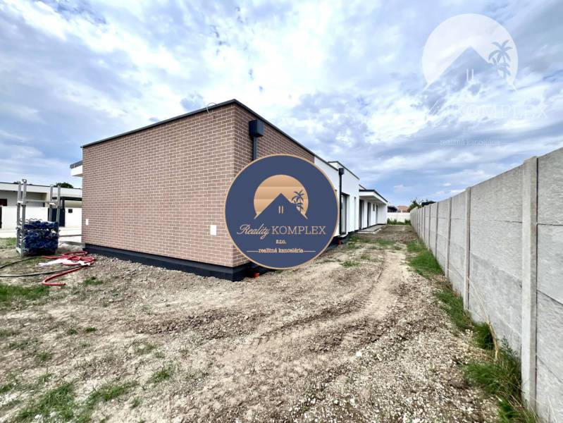 Ein Einfamilienhaus in Miloslavov mit einer Ziegelfassade und einem Grundstück neben einem Betonzaun.