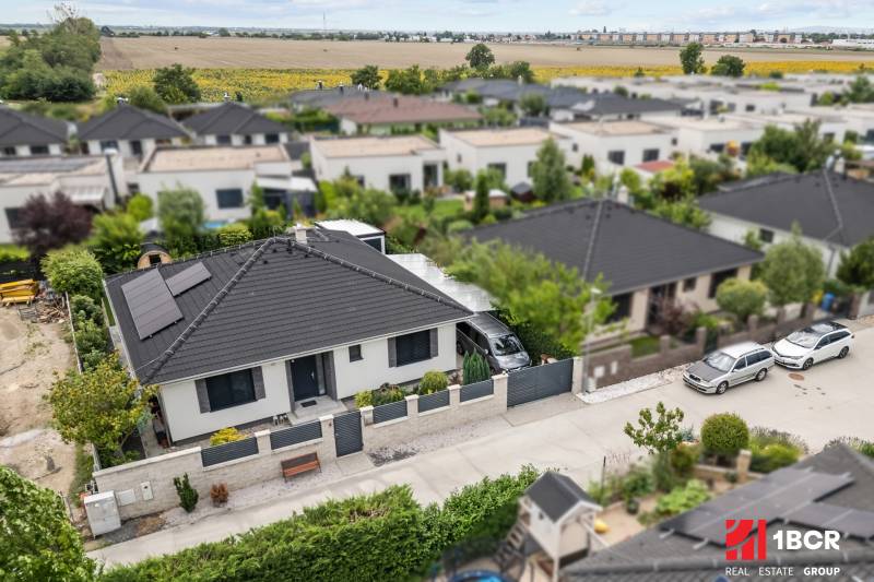 Ein Einfamilienhaus in der Feniklová-Straße in Malinovo mit Solarpanelen und Garten.
