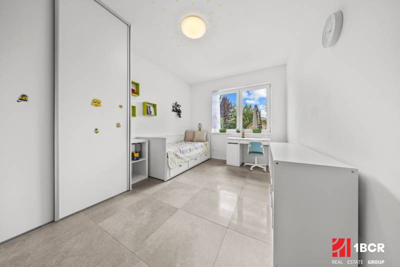Kinderzimmer im Einfamilienhaus mit Bett, Tisch und Schrank.