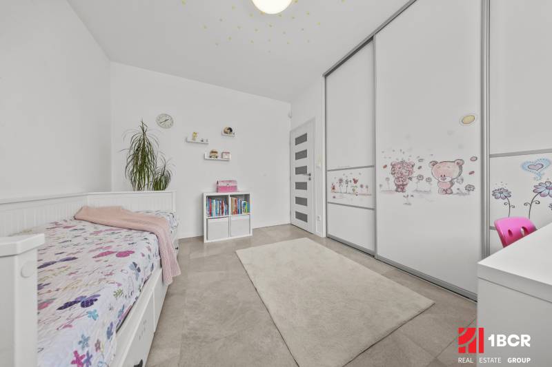 Kinderzimmer in einem Einfamilienhaus mit Bett, Bücherregal und Kleiderschrank mit Kindermotiv.