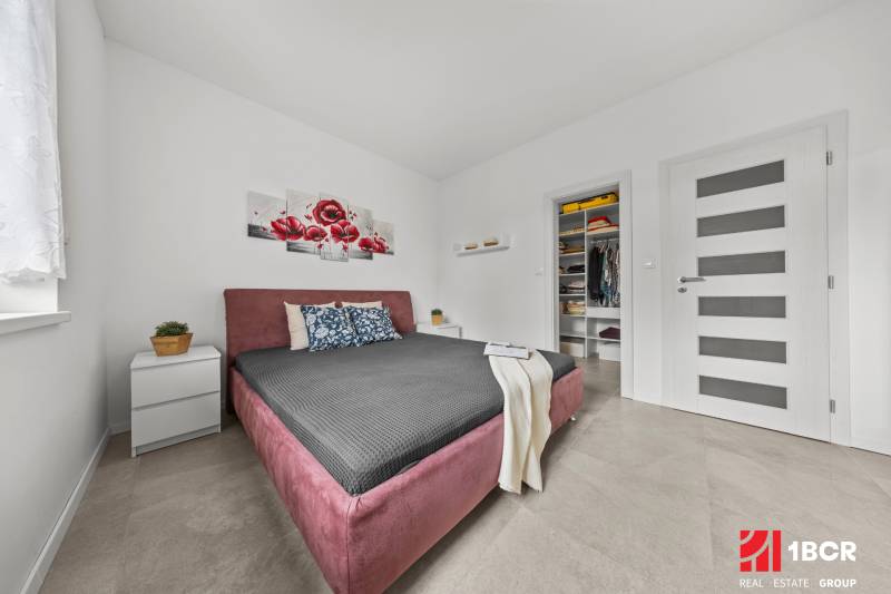 Schlafzimmer mit Einbauschrank, Bett und Dekoration mit roten Blumen in einem Einfamilienhaus.