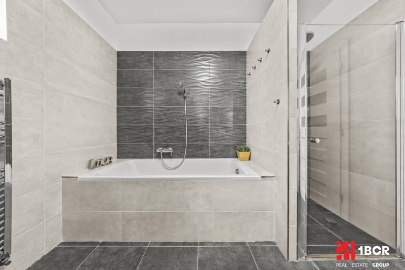 Graues Badezimmer mit Badewanne und Dusche in einem Einfamilienhaus.