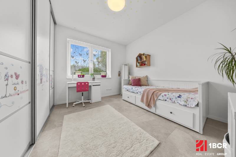 Kinderzimmer in einem Einfamilienhaus mit Schreibtisch, Bett und Schrank.