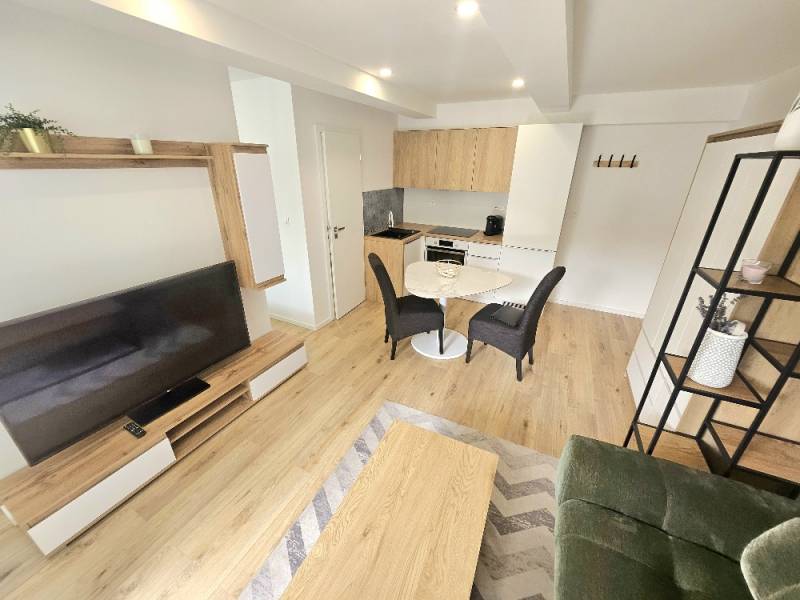 Wohnbereich mit Küchenzeile, Holzböden, Esstisch und TV-Wand.