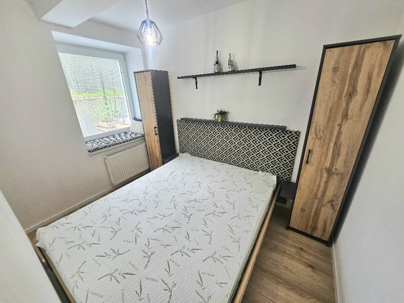 Schlafzimmer in einer Einzimmerwohnung mit Bett, Schrank und Dekorationen auf dem Regal.