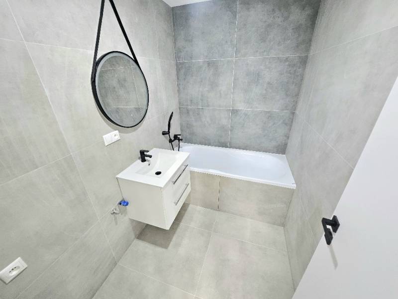 Badezimmer in einer 3-Zimmer-Wohnung mit Badewanne, Waschbecken und Spiegel an der Wand.