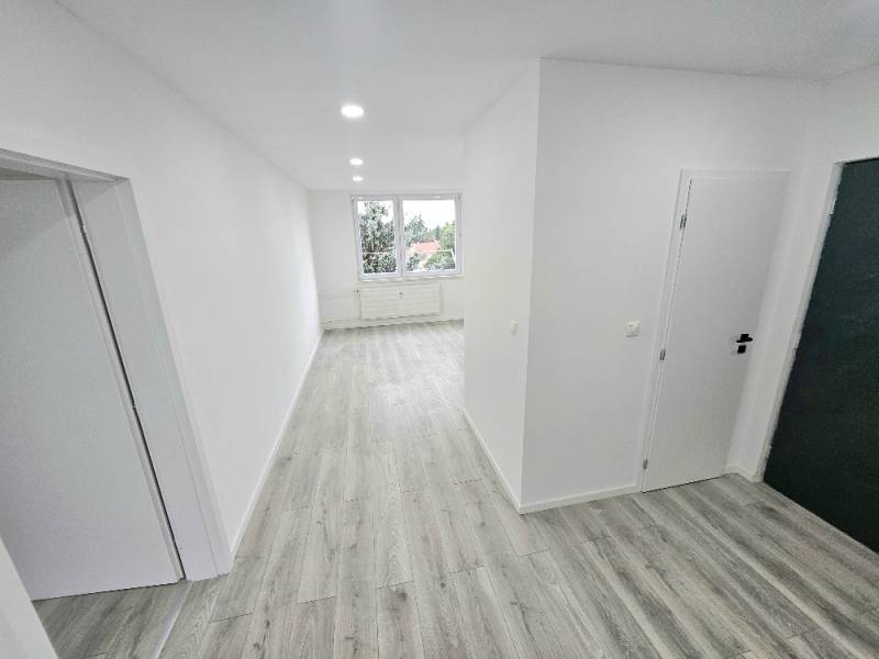 Flur in einer 3-Zimmer-Wohnung mit Holzboden und weißen Wänden.