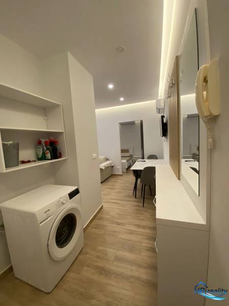Praktische Anordnung mit Waschmaschine und Esstisch im Ferienapartment.
