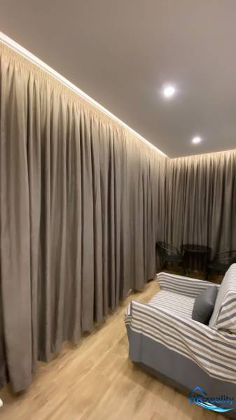 Vorhänge in einem farblich abgestimmten Interieur, Sofa und Sitzecke im Ferienapartment.