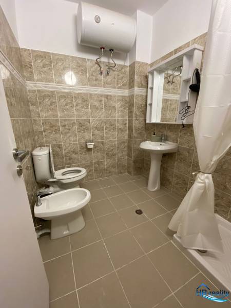 Badezimmer in einer Ferienwohnung; Waschbecken, Spiegel, Toilette, Bidet und Wassererhitzer.