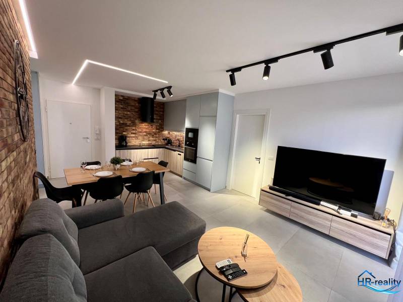 Das Wohnzimmer des Ferienapartments ist mit einer Küche, einem Esstisch und einem bequemen Sofa ausgestattet.