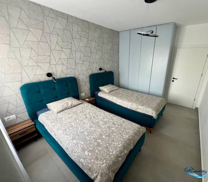 Doppelzimmer mit blauen Betten und gemusterter Wand im Ferienapartment.