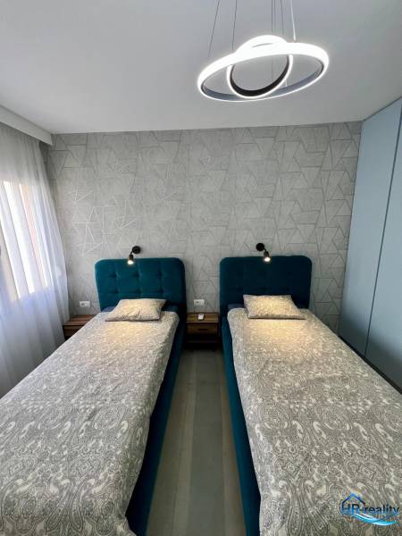 Doppelzimmer mit geometrischer Tapete und moderner Beleuchtung in einer Ferienwohnung.