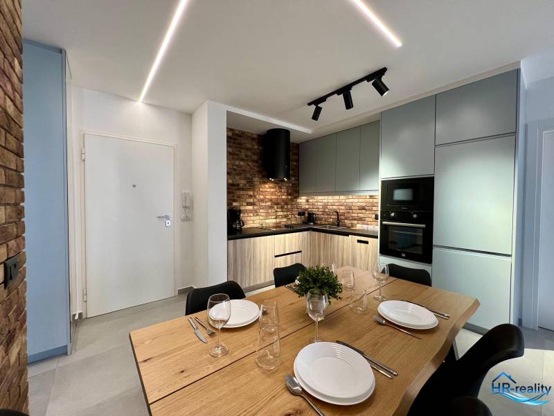 Küche in der Ferienwohnung mit Esstisch, Ziegelverkleidung und modernen Geräten.